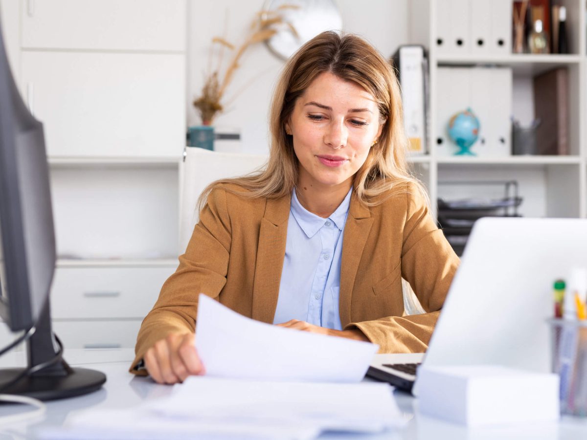 Woman working with papers and laptop